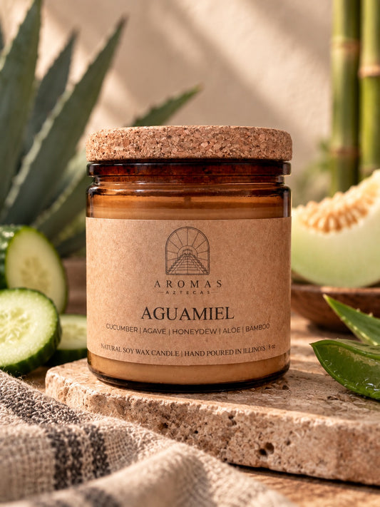Aromas Aztecas Aguamiel soy candle with a cork lid on a rustic stone surface, surrounded by subtle cucumber, honeydew, aloe, agave, and bamboo accents in a warm, natural setting.