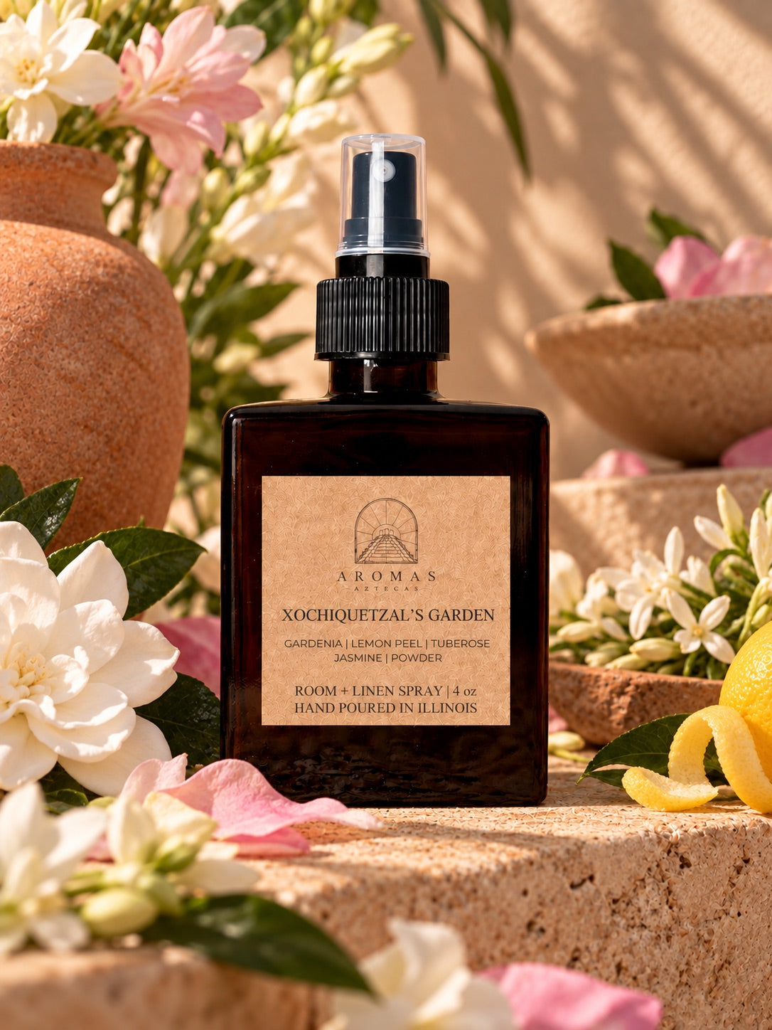 Aromas Aztecas Xochiquetzal’s Garden room and linen spray surrounded by gardenia, jasmine, tuberose, lemon peel, and greenery in a warm botanical setting.