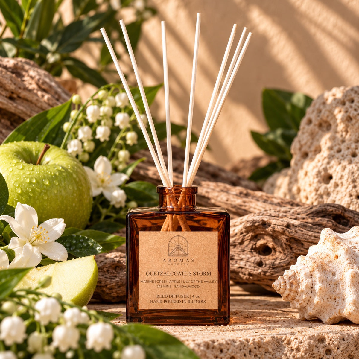Aromas Aztecas Quetzalcoatl’s Storm reed diffuser in an amber glass bottle with natural reeds, surrounded by green apple, jasmine, lily of the valley, tuberose, driftwood, and coastal-inspired elements against a sunlit background.