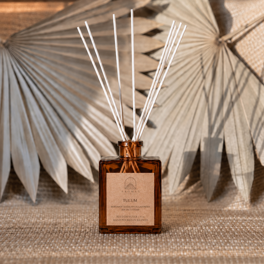 Aromas Aztecas Tulum reed diffuser in an amber glass bottle with natural reeds and dried palm leaf décor.